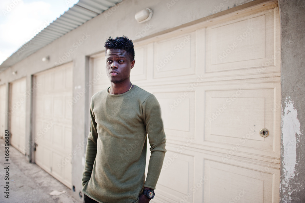 Portrait of an attractive black african american man posing and standing next to the garage gates. Portrait of an attractive black african american man posing and standing next to the garage gates.