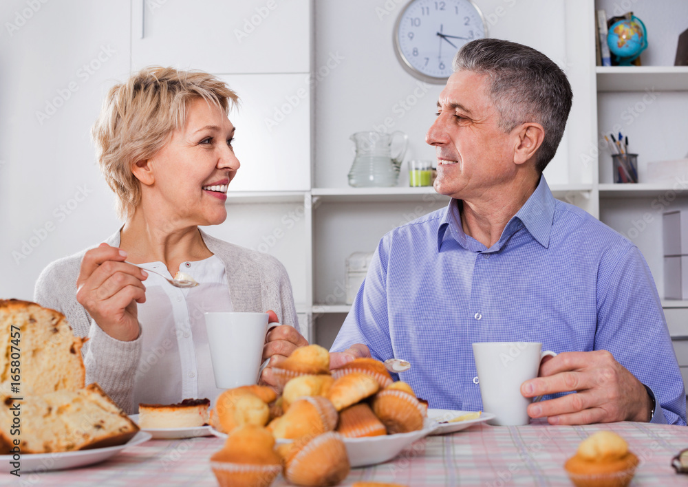 Mature couple have an afternoon snack with fresh muffins and cake