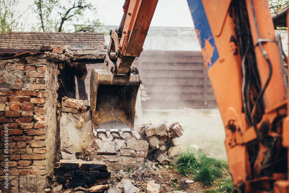 Fototapeta premium industrial bulldozer crushing an old building at construction site