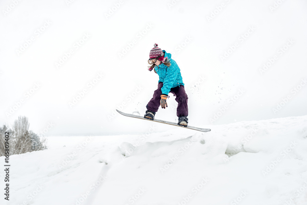 Young woman on the snowboard jumping