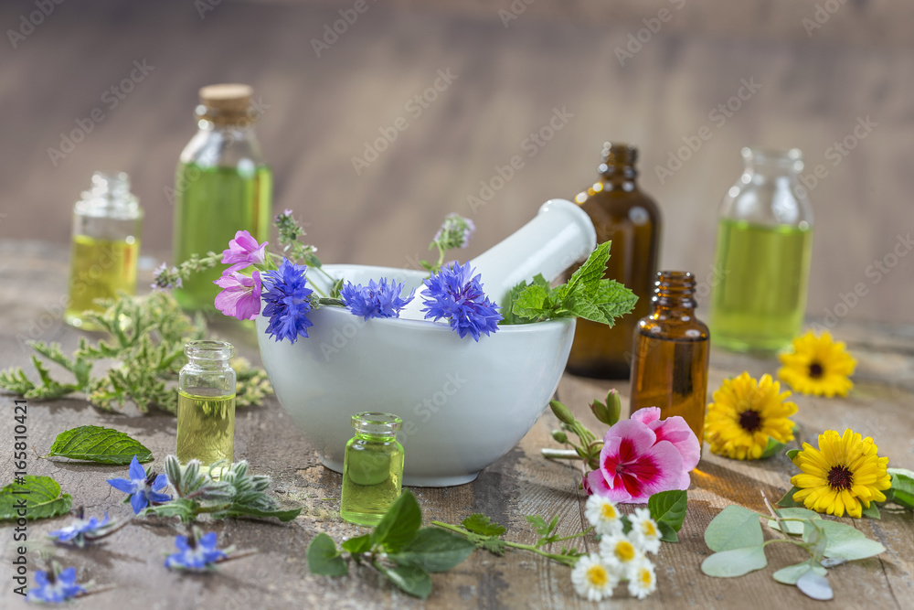 essential oils for aromatherapy treatment with fresh herbs in mortar, and essential oik bottle on the back on bleue wooden board background