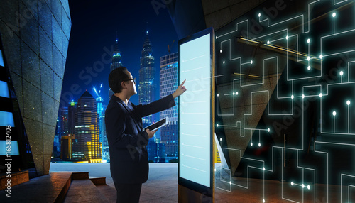 Smart businessman touch the screen to search the information of intelligent communication network of things . Night scene with modern city background . © jamesteohart