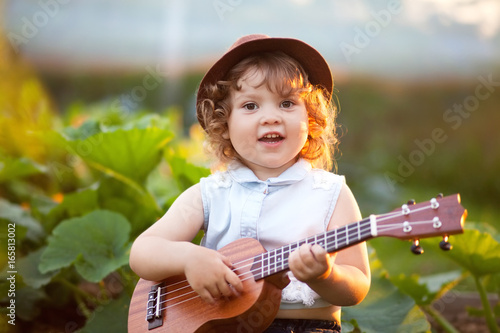 Little girl playing ukulele outdoors