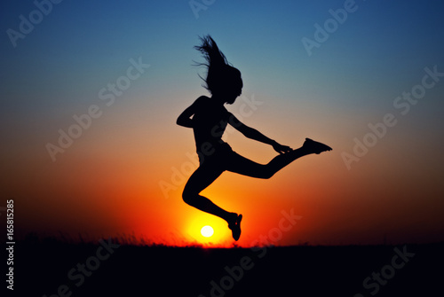 teen girl jumping at sunset. silhouette photo