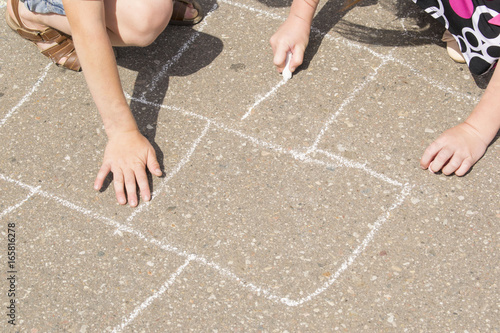 Children playing outside and drawing on the asphalt.