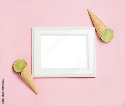 white wooden frame on pink background decorated with lime in waffle cone, blank space for a text. Top view, flat lay