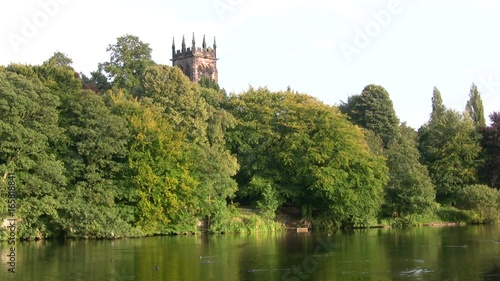 A tranquil English countryside scene with a church tower rising above tall leafy trees at the lakeside, Lymm Dam in Cheshire. photo