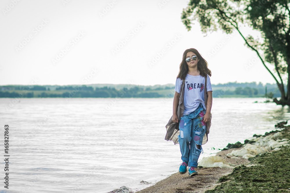 Portrait of little fashionable girl walking on berth near sea Portrait of little fashionable girl walking on berth near sea