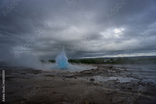Iceland - Turquoise hot boiling water, beginning of eruption of geyser strokkur with trees
