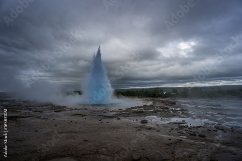Iceland - Turquoise hot boiling water, summit of eruption of geyser strokkur with trees