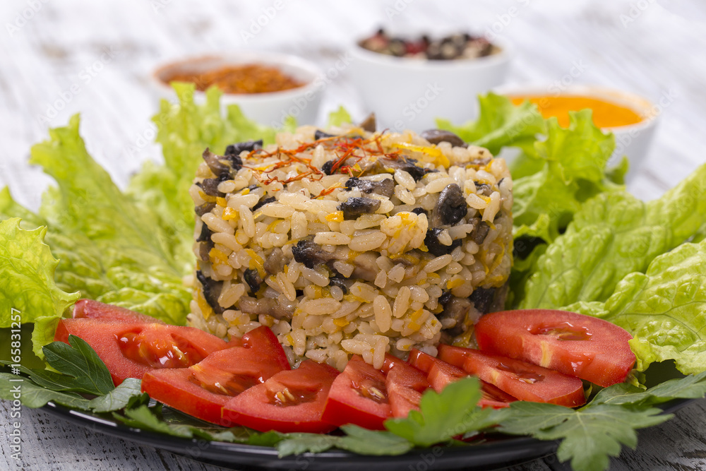 Rice with mushrooms and green lettuce leaves on rustic table background