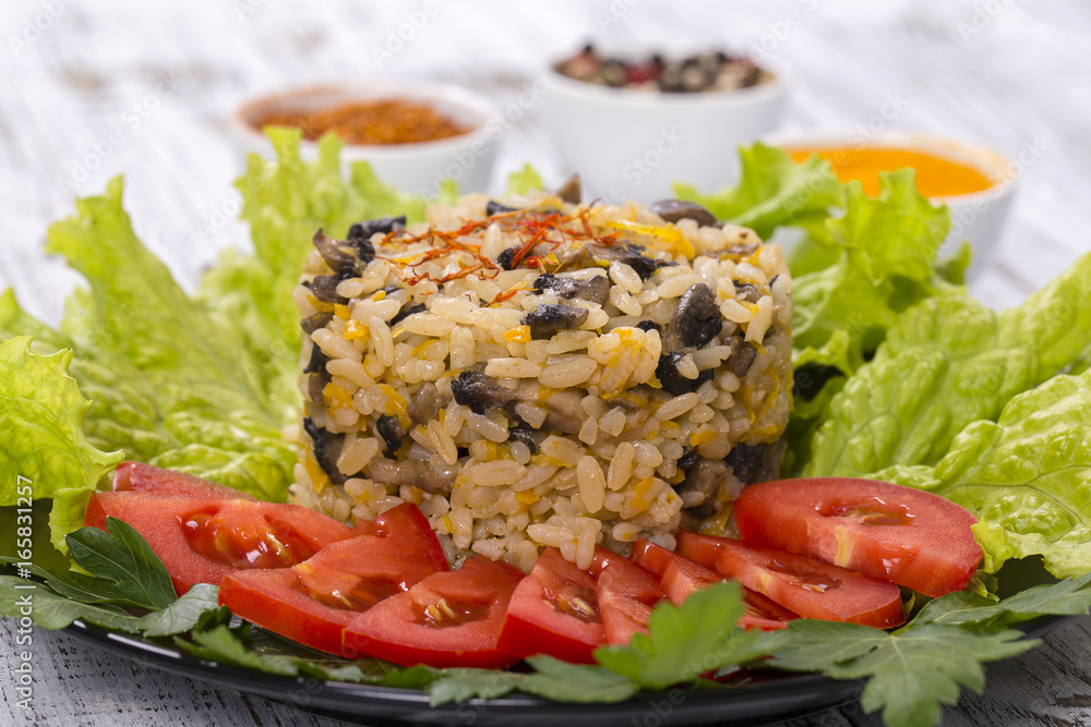 Rice with mushrooms and green lettuce leaves on rustic table background Rice with mushrooms and green lettuce leaves on rustic table background