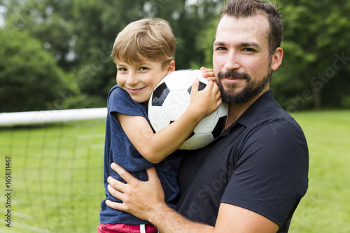 Young father with his little son playing football on football pitch © Louis-Photo