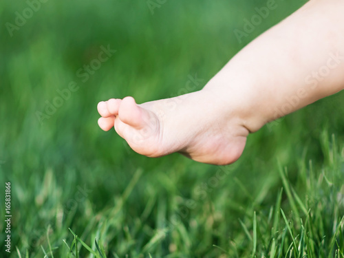 Baby leg making first step on green grass © Tetiana