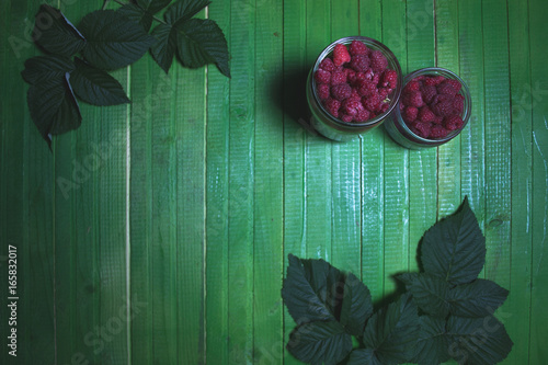 Fresh ripe raspberries on green wooden boards.