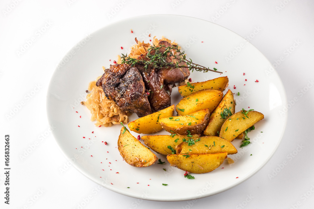 Delicious grilled duck wings with potatoes and stewed cabbage on a white plate