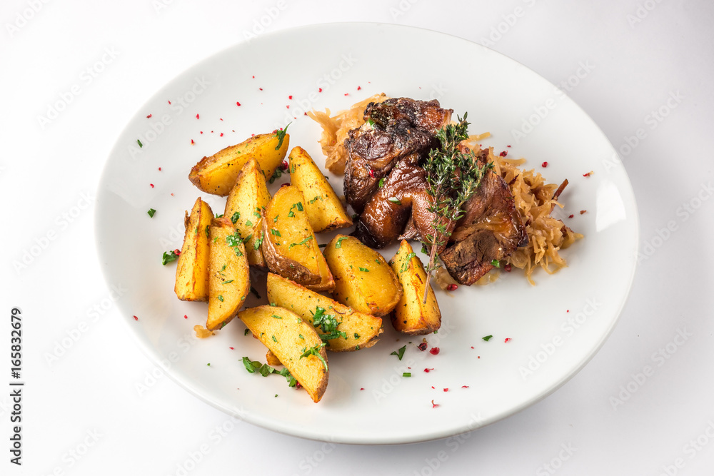 Delicious grilled duck wings with potatoes and stewed cabbage on a white plate