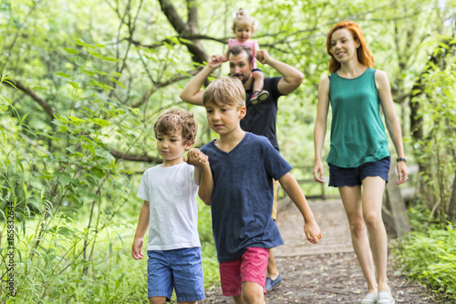 Happy young family walking outside in green nature
