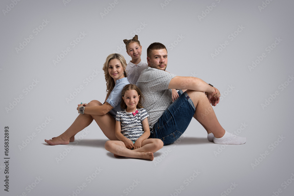 Young family lying on floor and posing on grey studio background Stock  Photo | Adobe Stock