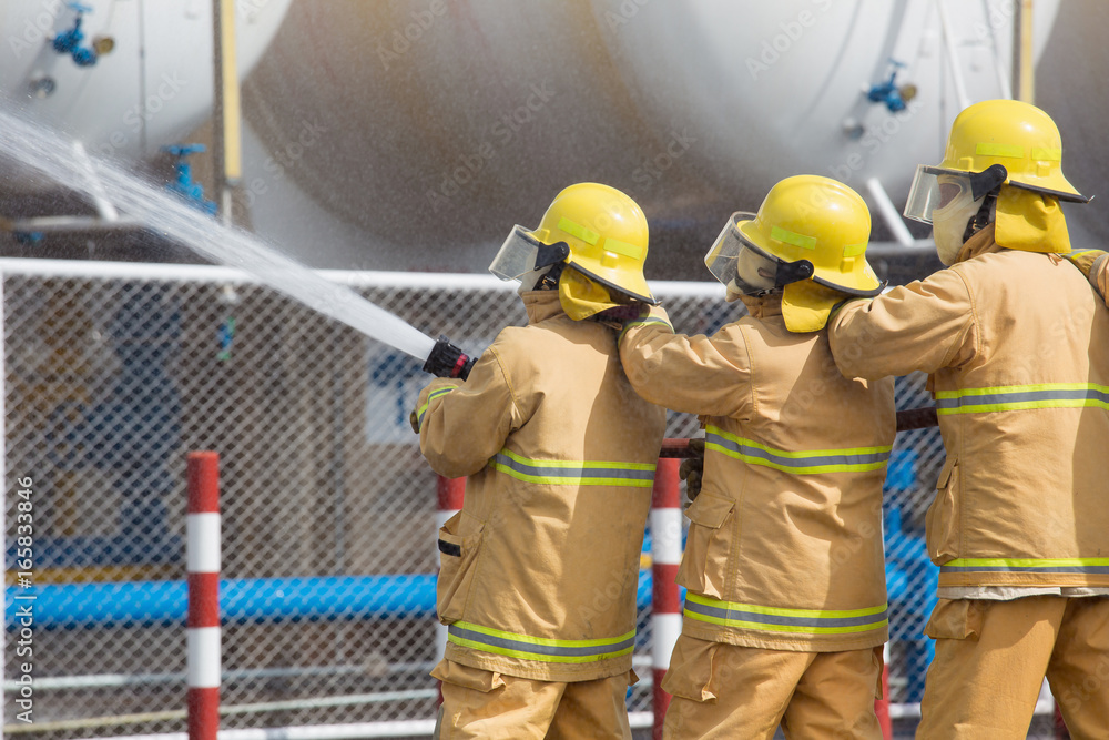 Naklejka premium Firefighters spray water in LPG gas tanks, Fire extinguishers caused by explosive gas