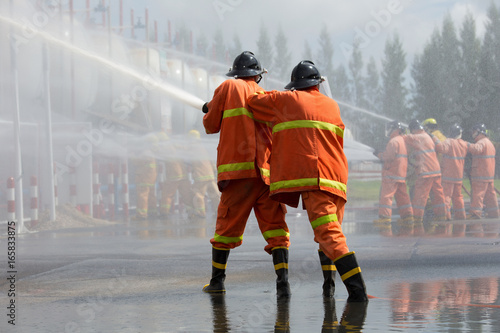 Fotografi Firefighters spray water in fire extinguishers caused by explosive gas