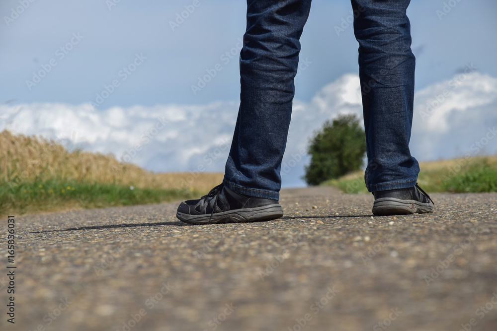 A man is standing on the road. Legs close-up.