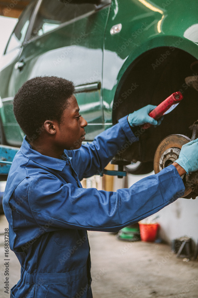 Young mechanic checking a vehicle's brakes in a garage. Young mechanic checking a vehicle's brakes in a garage.
