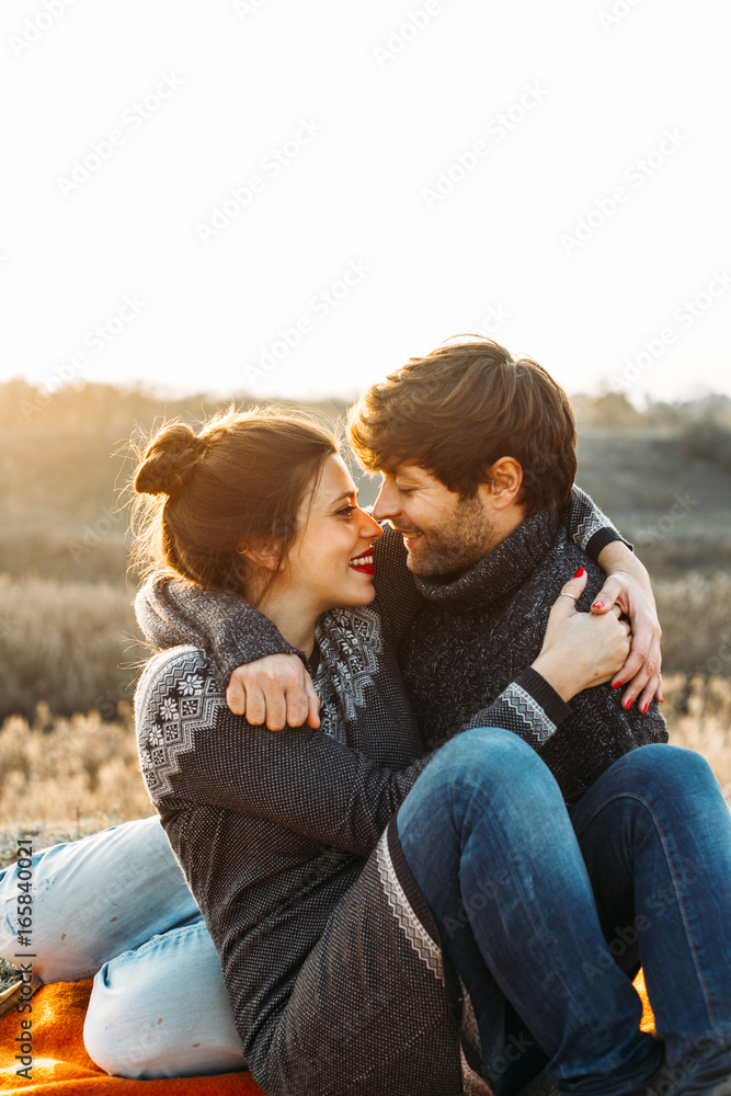 Embracing couple sitting on a blanket. Embracing couple sitting on a blanket.