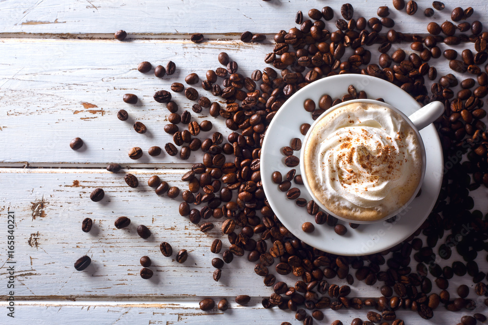 Φωτογραφία Top view of an irish coffee in a cup with coffee beans around over a white wood