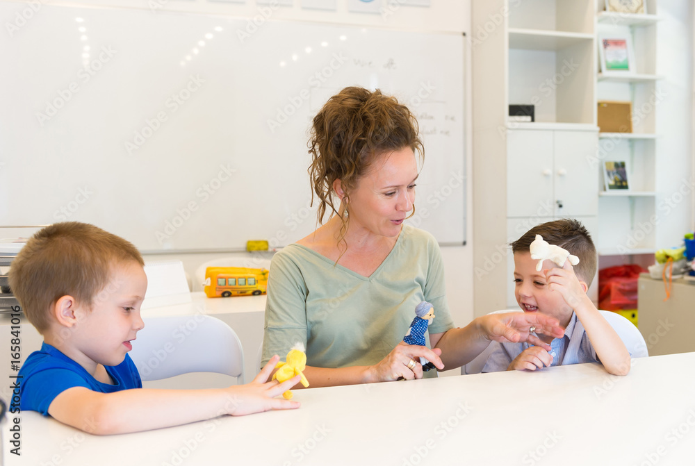 teacher woman playing with two child boy with finger puppets in the classroom teacher woman playing with two child boy with finger puppets in the classroom