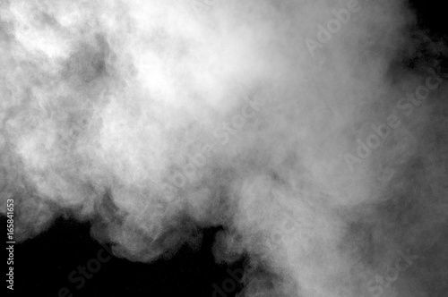 Freeze motion of white dust explosion on black background. Stopping the movement of white powder on dark background. Explosive powder white on black background.