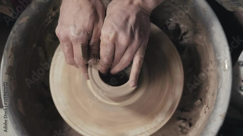 Hands of the master potter and vase of clay on the potter's wheel close-up. Master crock man. Twisted potter's wheel. photo