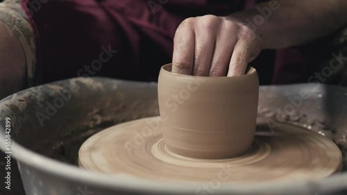 Hands of the master potter and vase of clay on the potter's wheel close-up. Master crock man. Twisted potter's wheel. photo