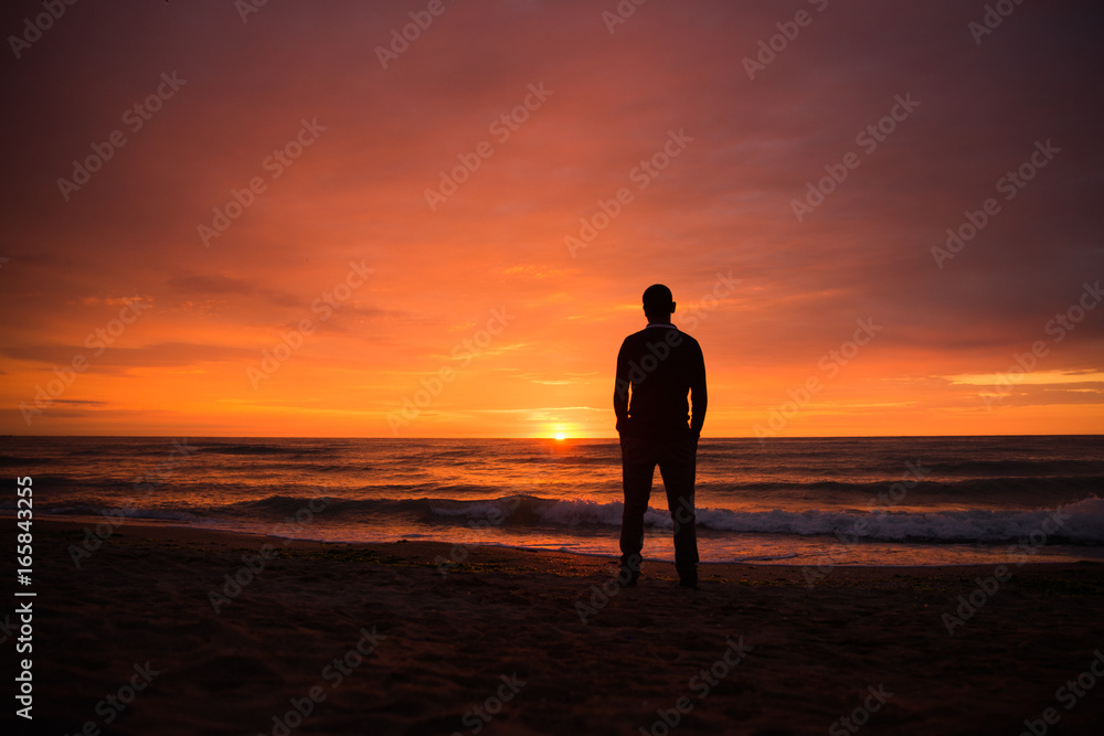 Lonely single man watching a beautiful dramatic sunset