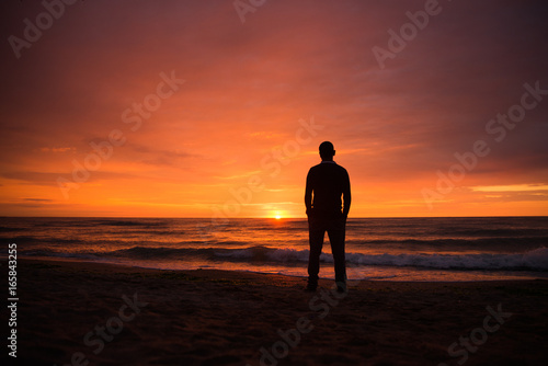 Lonely single man watching a beautiful dramatic sunset