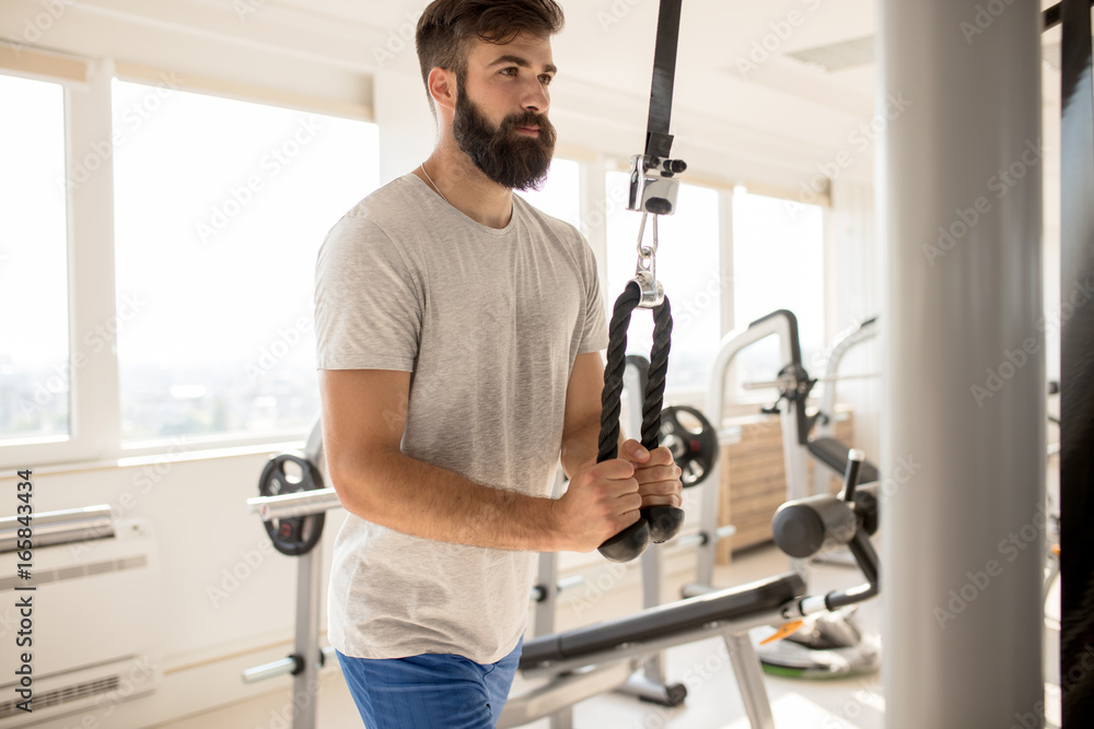 Fit man exercising at the gym on a machine Fit man exercising at the gym on a machine