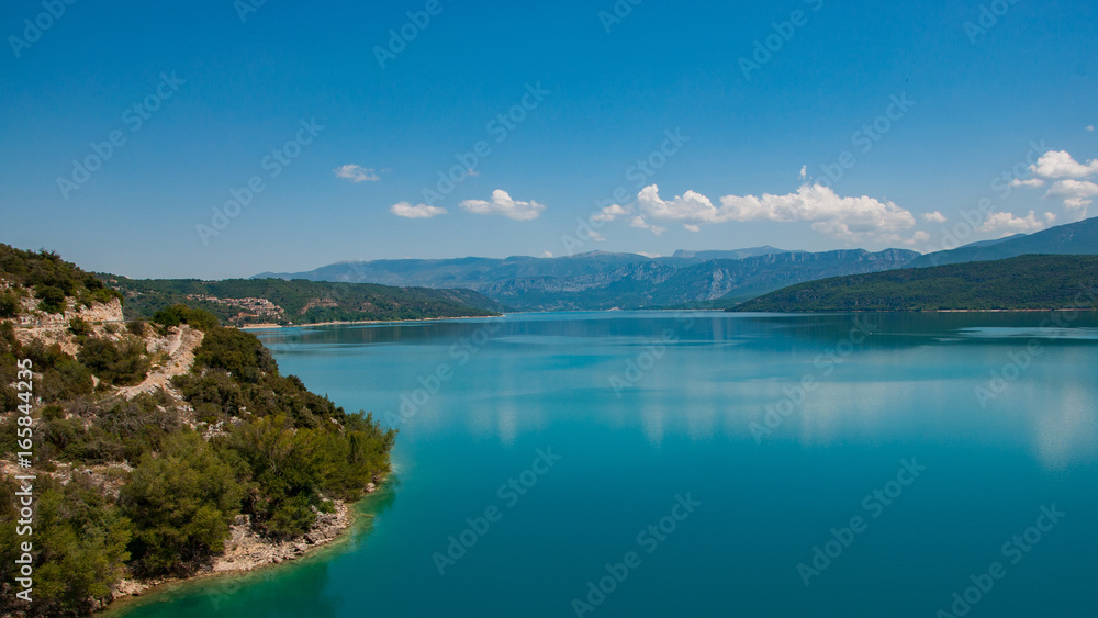 Lac de haute montagne avec plage et ciel bleu se reflétant dans une eau bleue turquoise en forme de carte postale