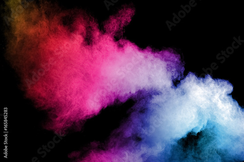 Abstract art colored powder on black background. Frozen abstract movement of dust explosion multiple colors on black background. Stop the movement of multicolored powder on dark background.