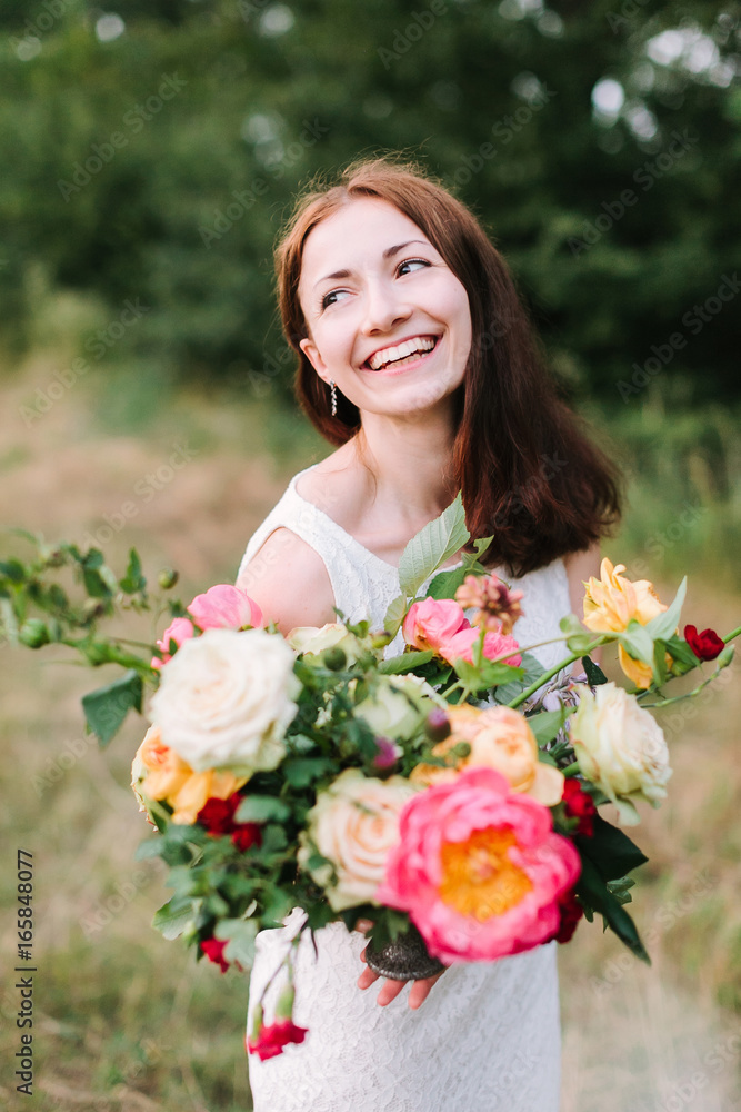bouquet, people and floral arrangement concept - young smiling woman with brown hair and colourful bouquet in hands, pink peonies, roses, carnations, happy female in white dress on background of trees bouquet, people and floral arrangement concept - young smiling woman with brown hair and colourful bouquet in hands, pink peonies, roses, carnations, happy female in white dress on background of trees
