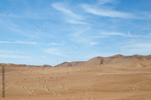 Sands of the desert under bright blue sky with few clouds