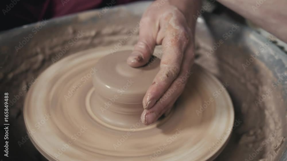 The hands of a potter, creating an earthen jar on the circle, close-up, hands on circle with clay The hands of a potter, creating an earthen jar on the circle, close-up, hands on circle with clay