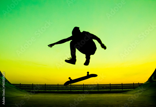 Young skateboarder does the trick on a bright green background
