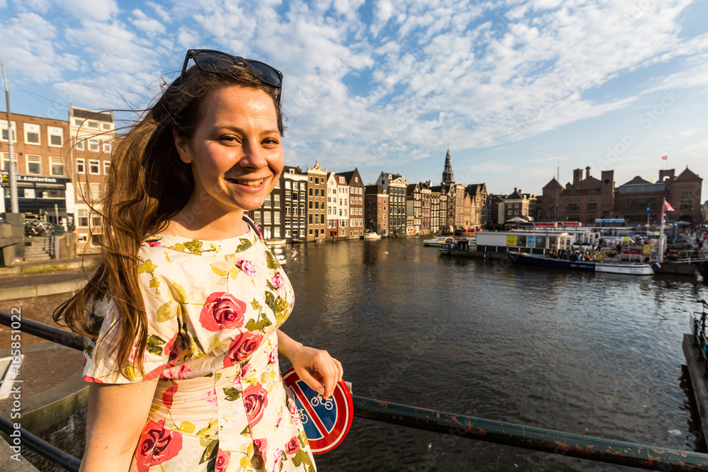 Tourist girl on sunset at the Damrak square in Amsterdam