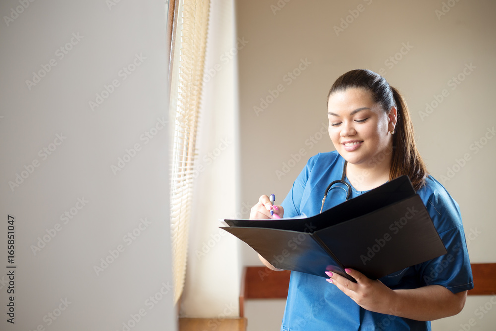 Fototapeta premium Young hispanic female doctor smiling, holding a report and looking into folder she is holding in her hands