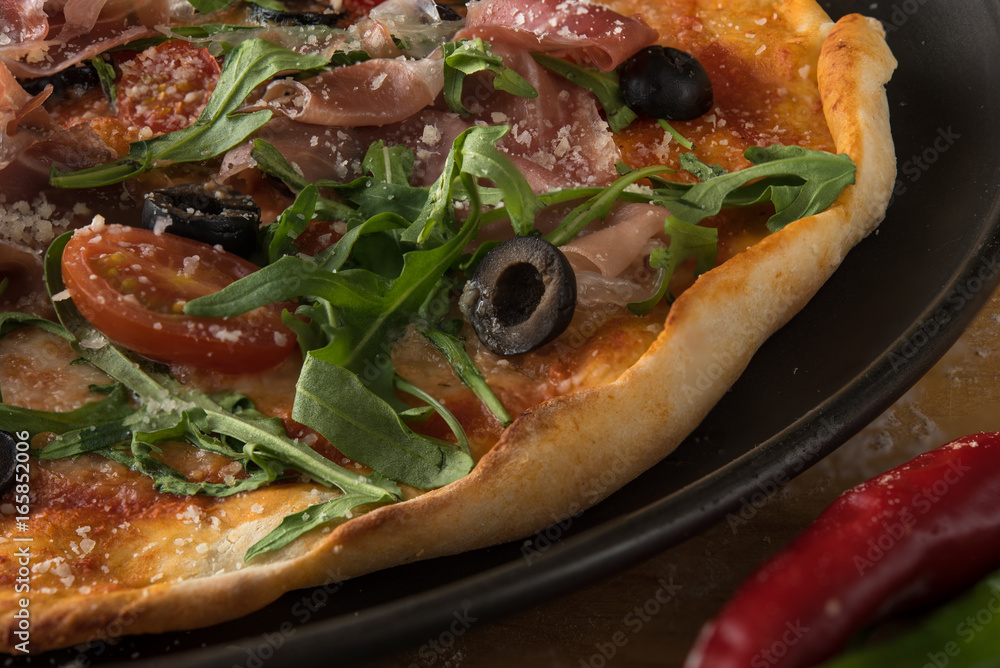Traditional pizza with prosciutto and arugula Traditional pizza with prosciutto and arugula