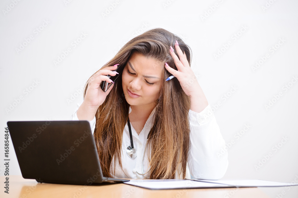 Young female hispanic doctor having headache from too much office work to deal with Young female hispanic doctor having headache from too much office work to deal with