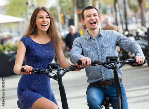 Happy young man and woman with electrkc bikes photo