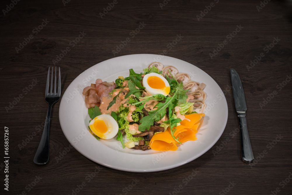 Salad with egg and mushrooms on a white plate and a wooden background