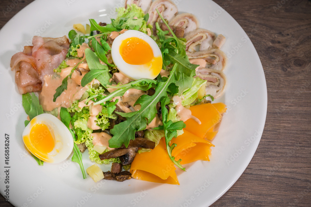 Salad with egg and mushrooms on a white plate and a wooden background Salad with egg and mushrooms on a white plate and a wooden background