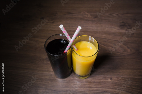 Two fresh glasses of juice with a straw